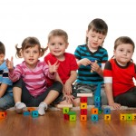 Five children are playing on the floor together